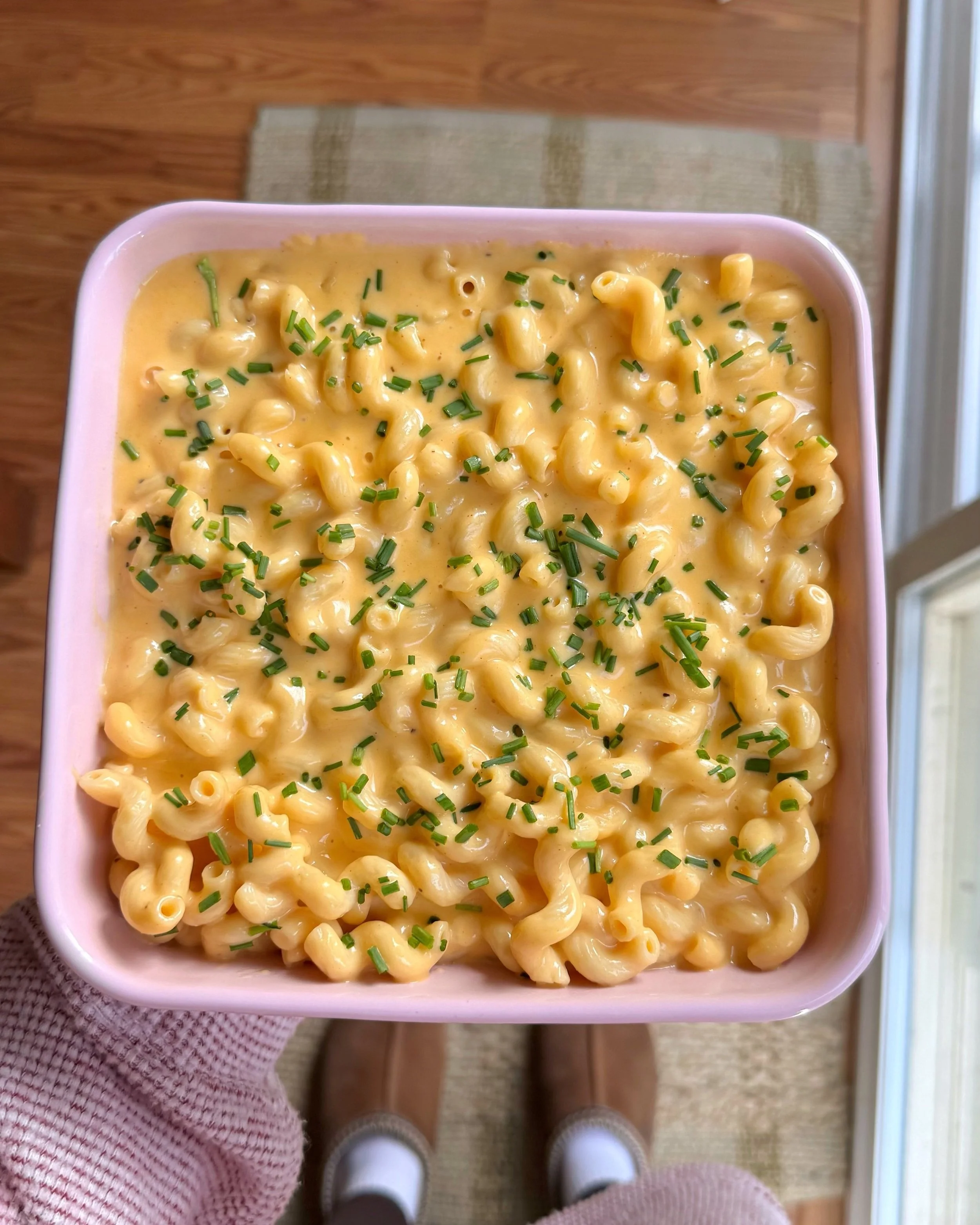 A baking dish with mac & cheese in it with fresh chopped chives on top. 