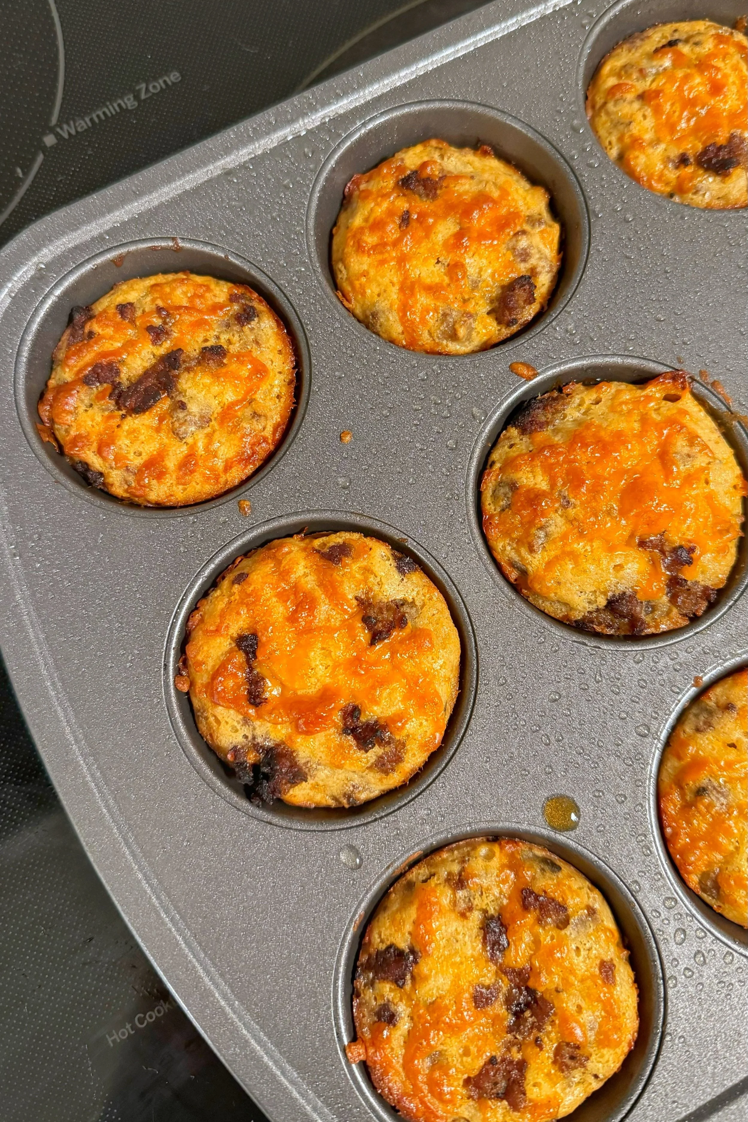 A muffin tin with sausage cheddar muffins.