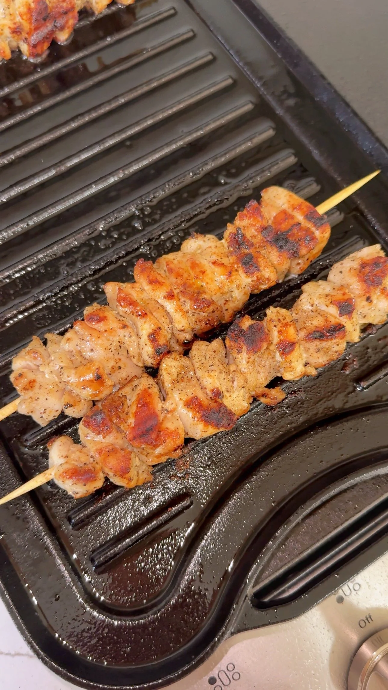 Chicken skewers cooking on top of an oven grill.