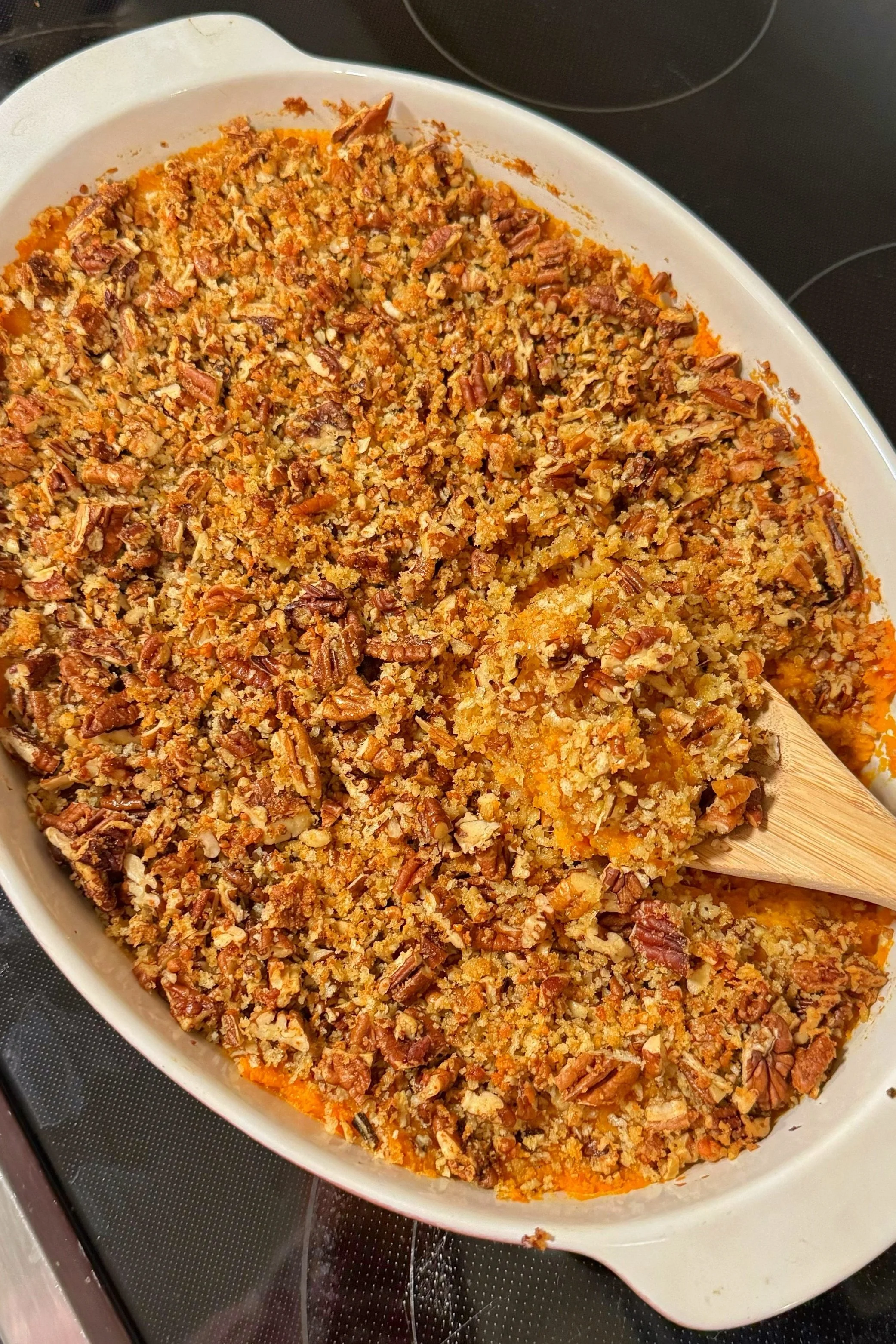 A baking dish with a sweet potato casserole topped with pecans.