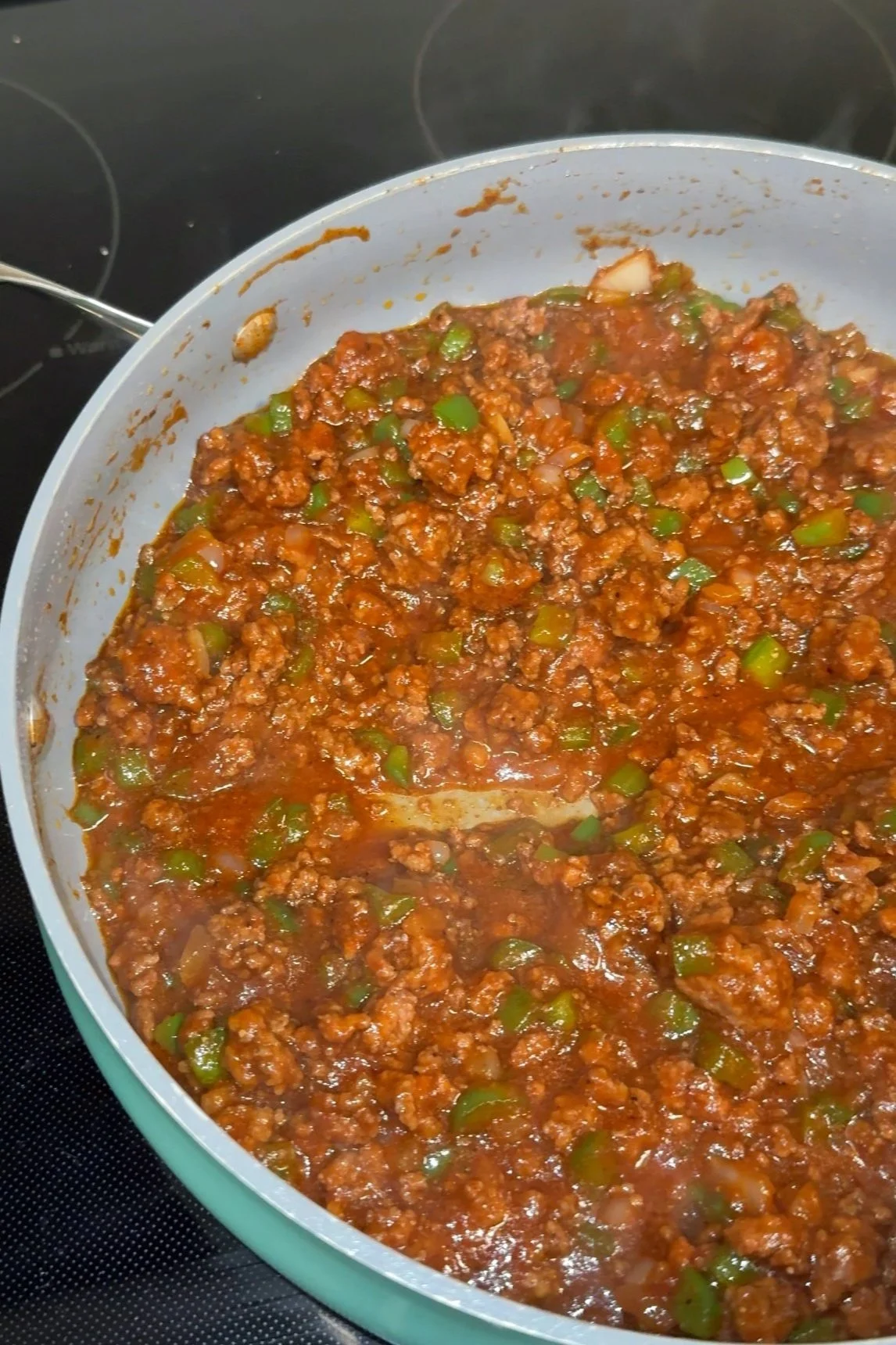 A frying pan with sloppy Joe meat mixture inside of it. 