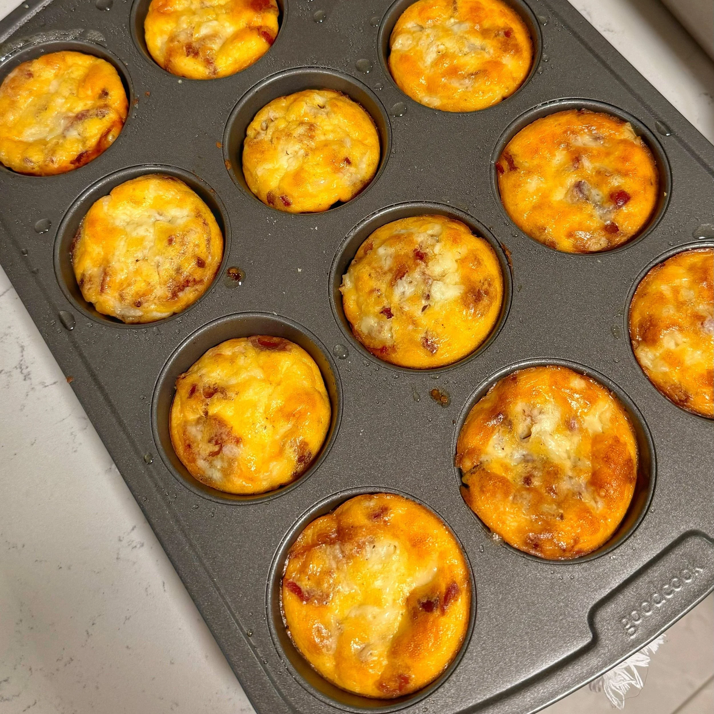 A muffin tin filled with bacon cheddar egg bites. 