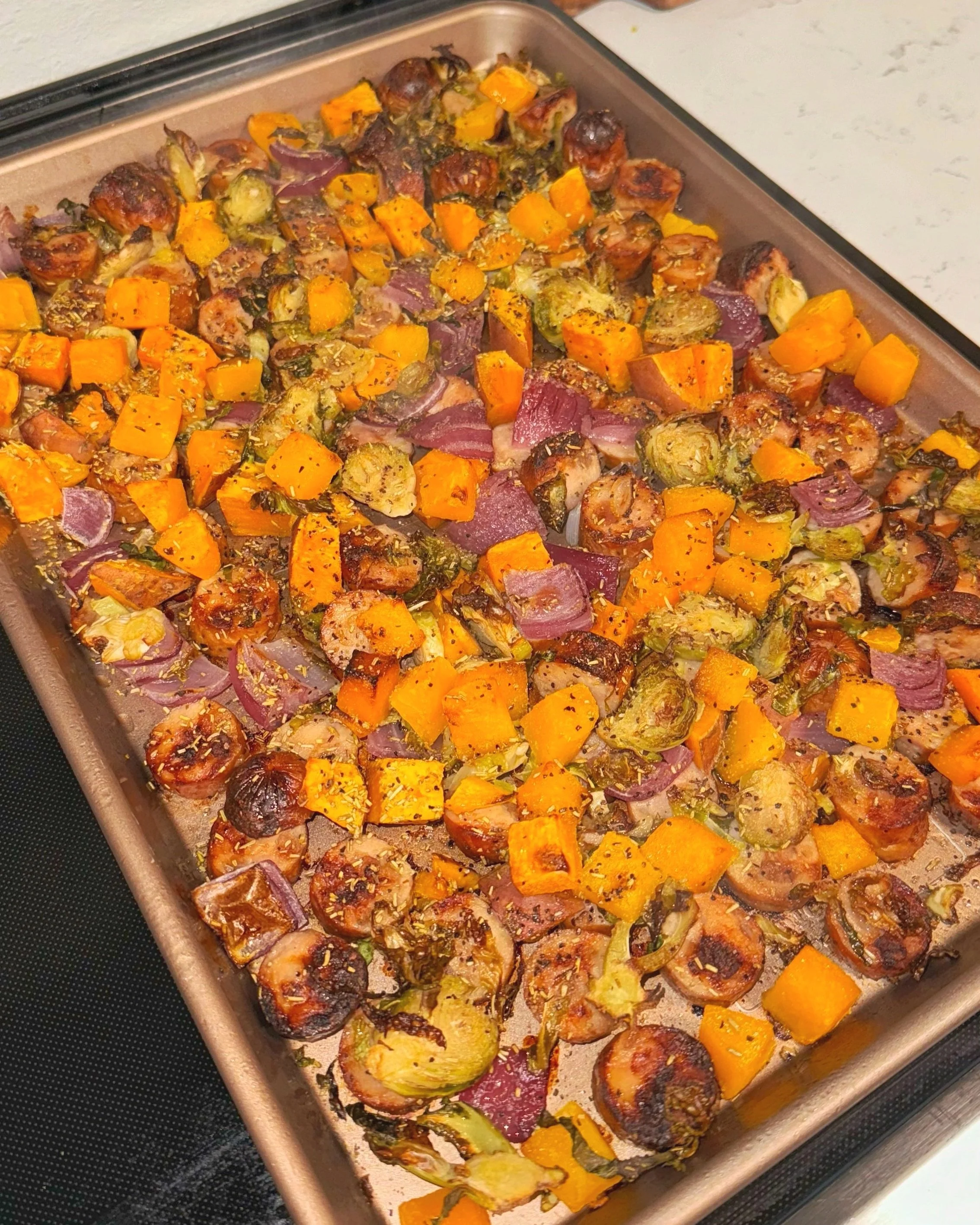 A sheet pan of apple chicken, sausage, and roasted veggies.