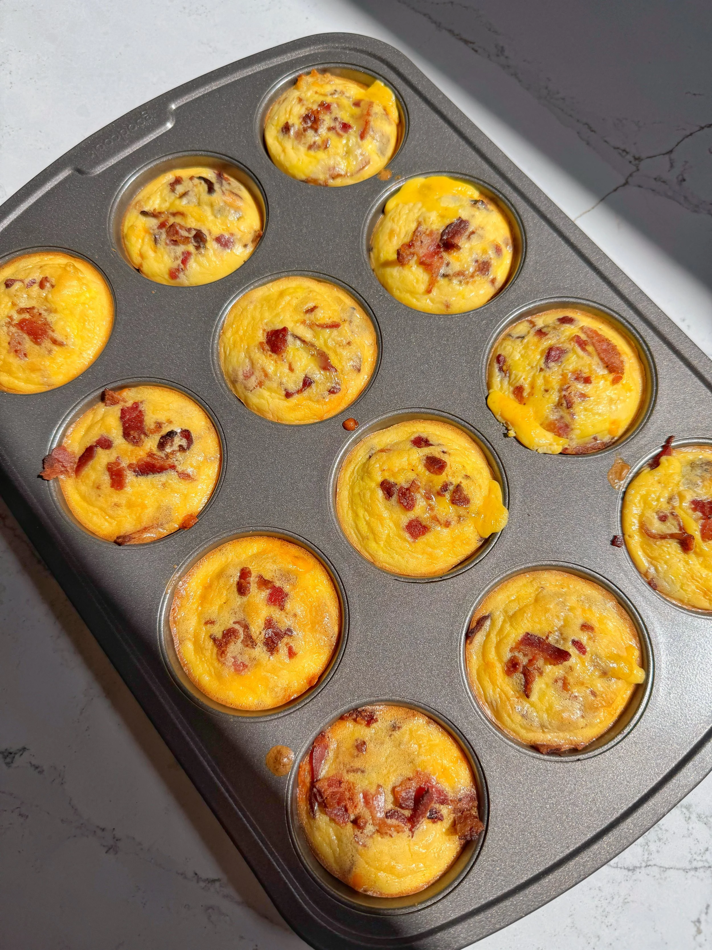 A muffin pan filled with cheesy hash brown egg bites.