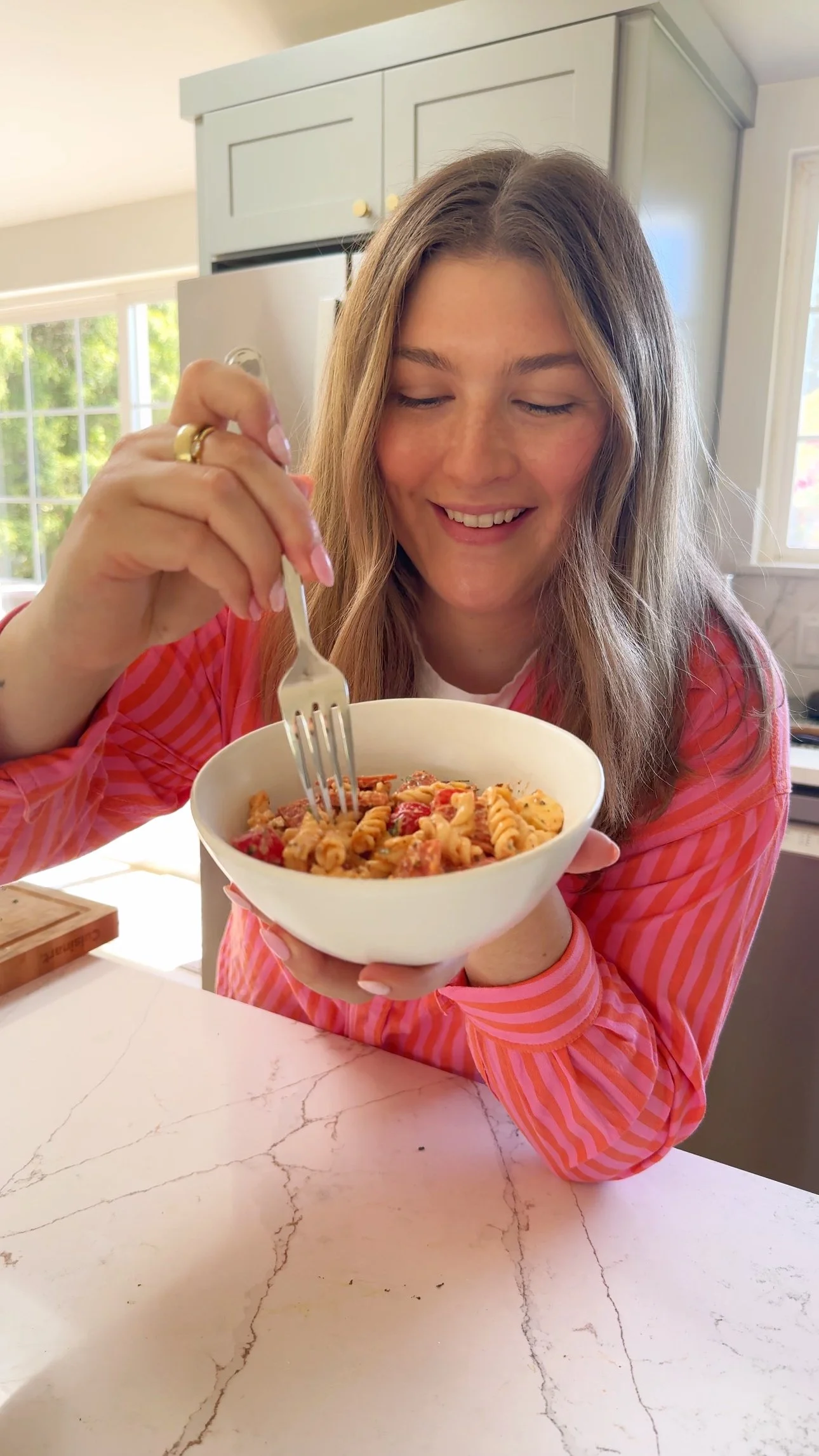 A bowl being held up that has hot honey pasta with tomatoes, mozzarella balls and fresh basil.