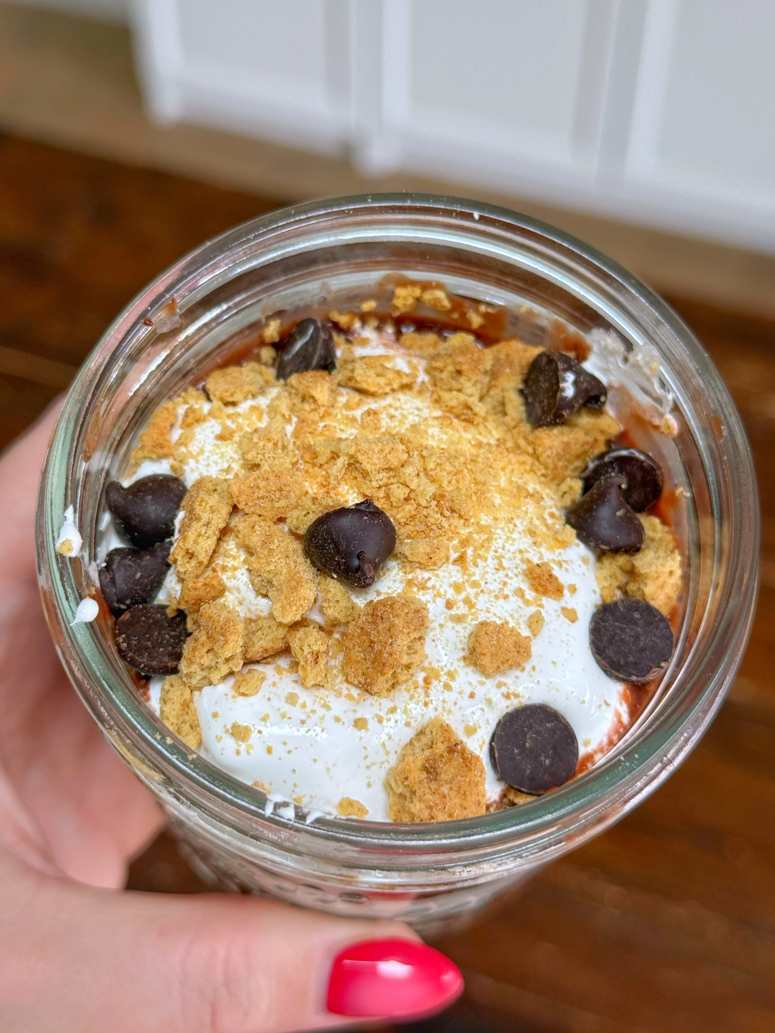 A close up shot of a jar of s'more pudding with graham crackers and chocolate chips on top. 