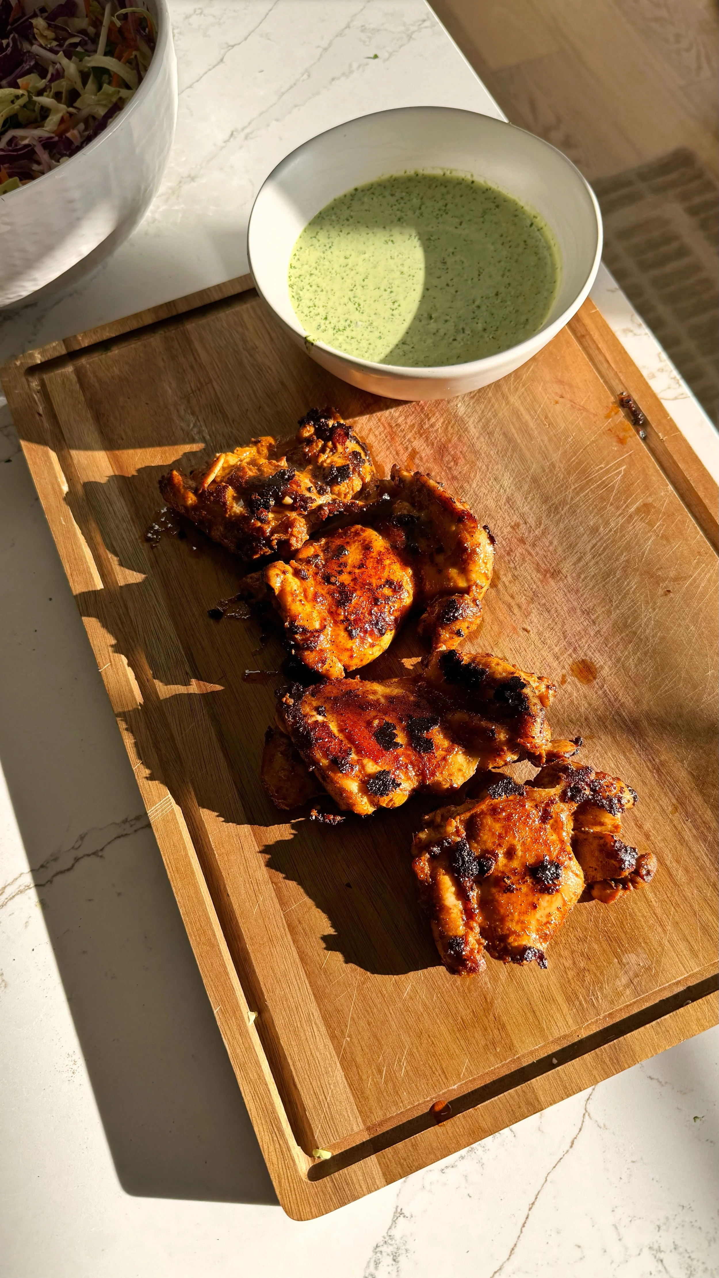 Crispy grilled chicken sitting on top of a cutting board.