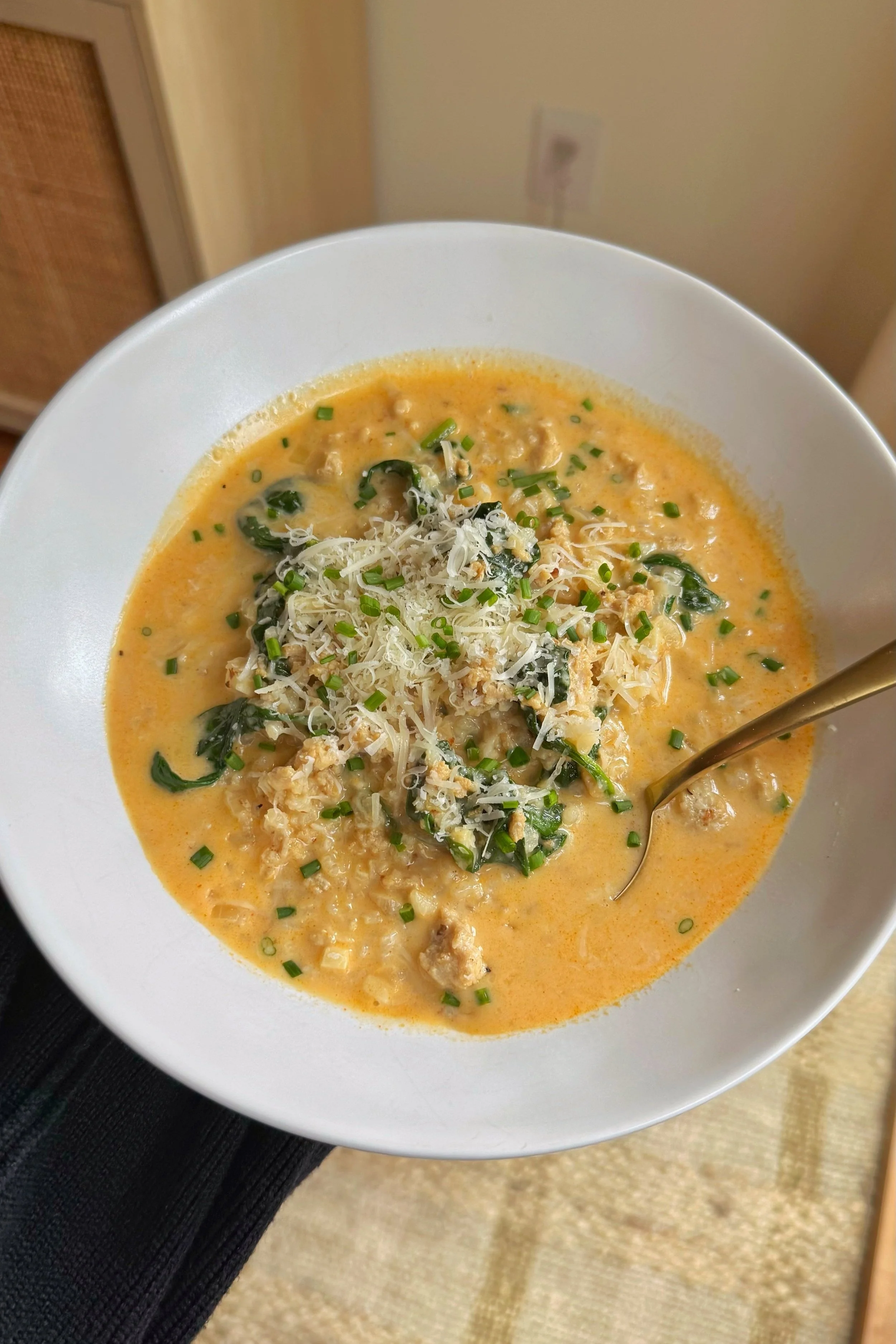 A bowl of creamy garlic soup with Parmesan cheese, chopped chives on top served with a side of toasted bread.