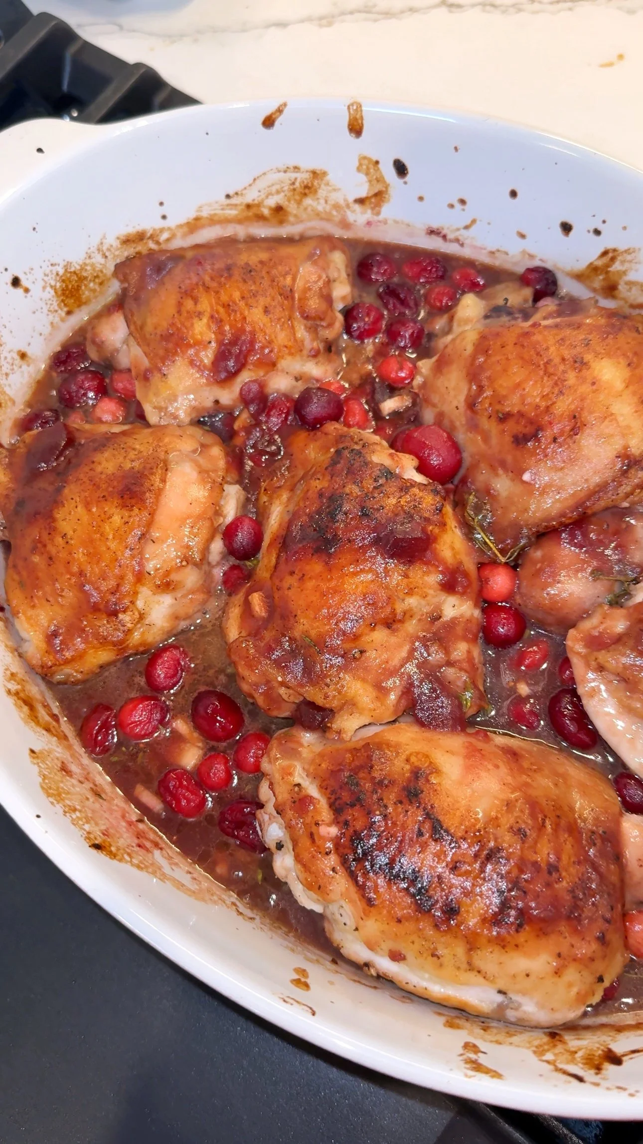 A close up shot of a casserole dish with cranberry orange chicken bake in a glaze.