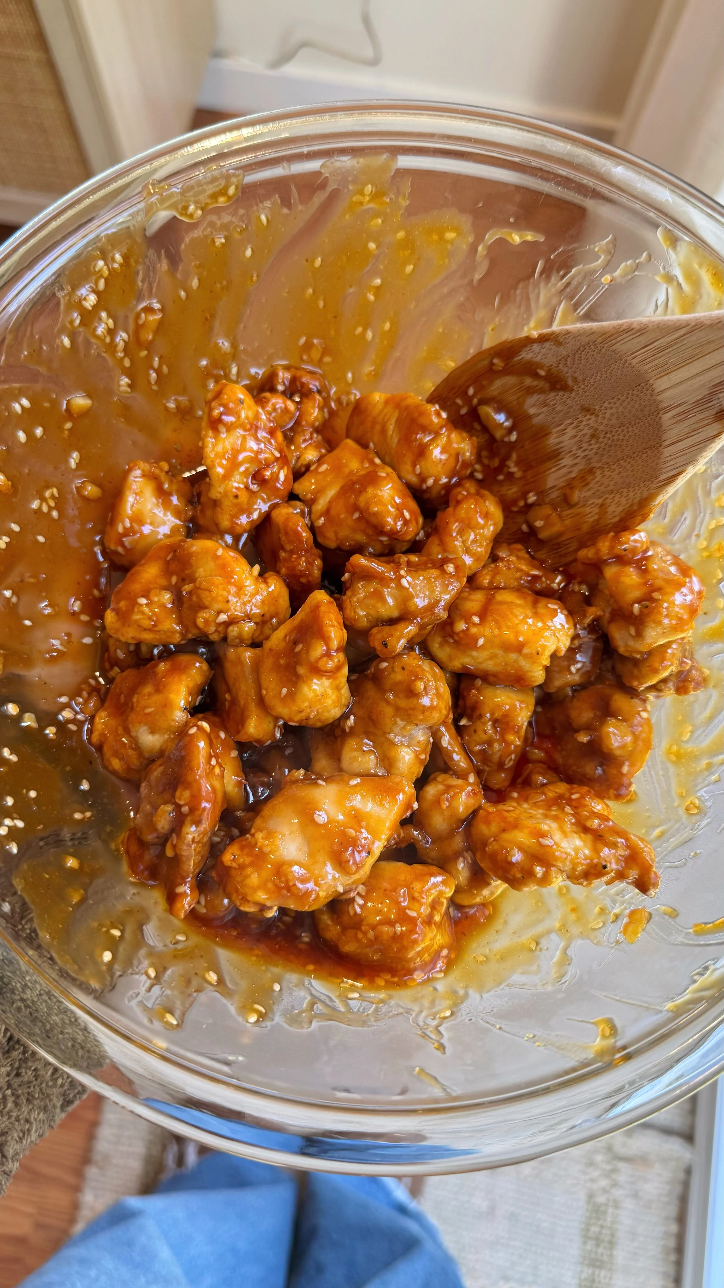 A serving bowl with crispy honey chicken with sesame seeds.