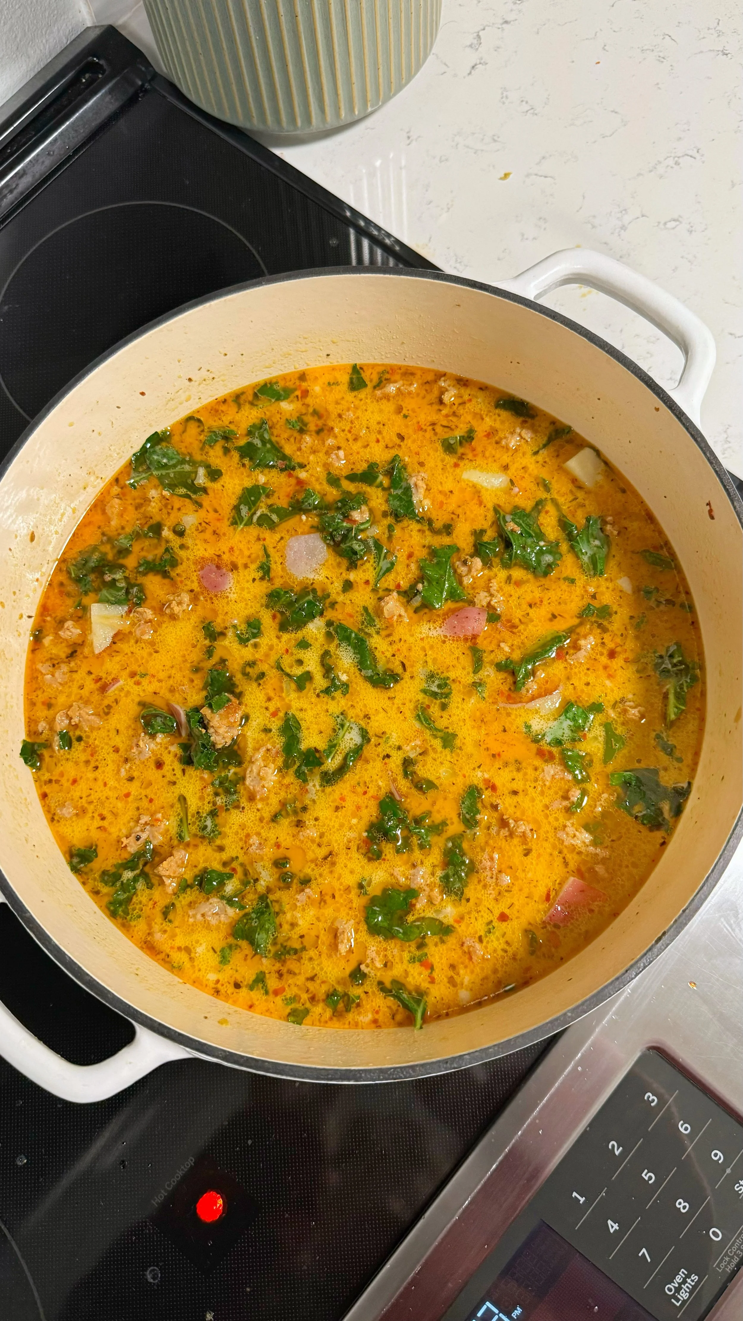 A pot of soup with ground chicken, potatoes and kale.