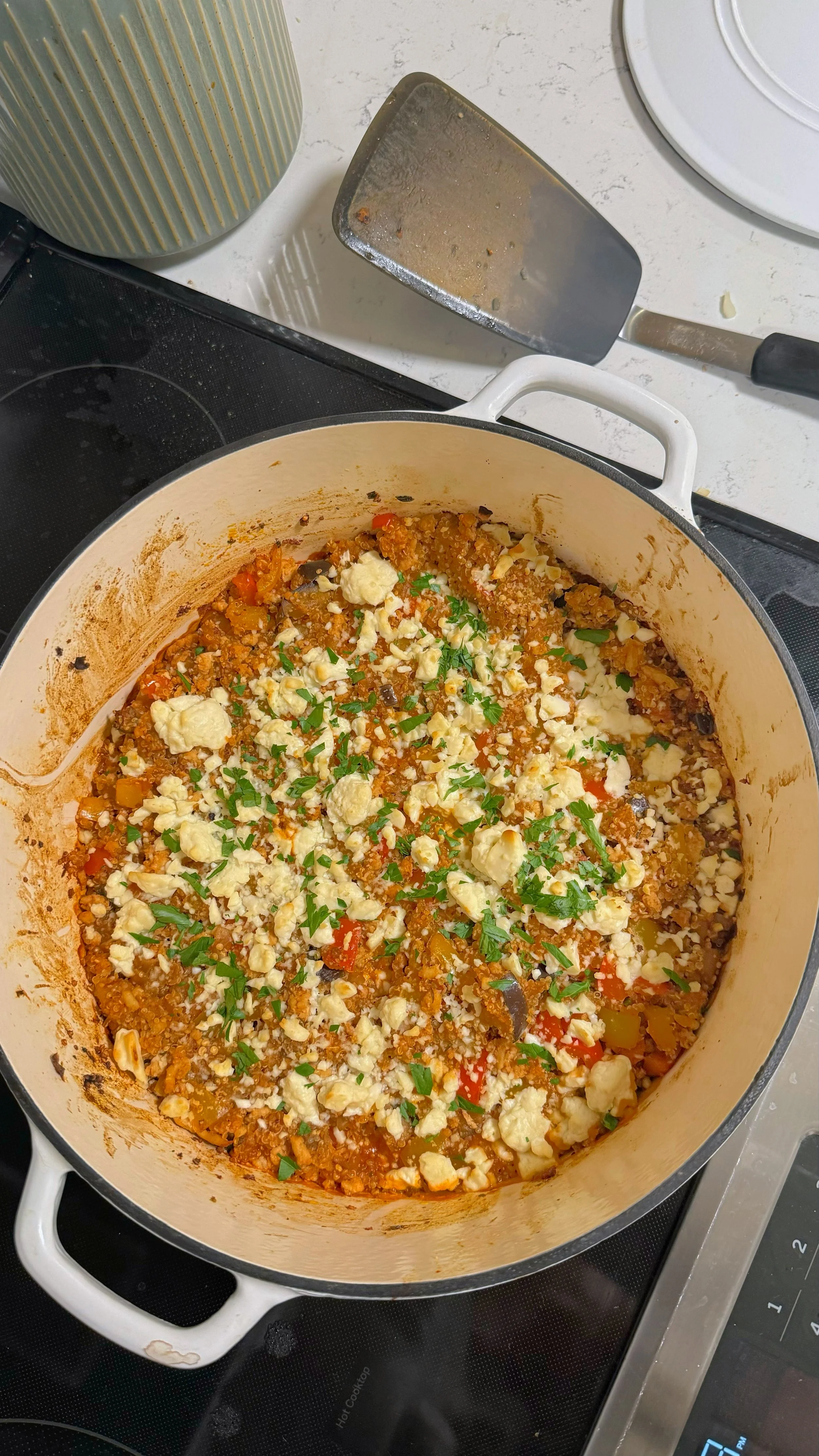 A pot of ground chicken, red peppers & eggplant mixed with quinoa topped with feta cheese & fresh parsley.