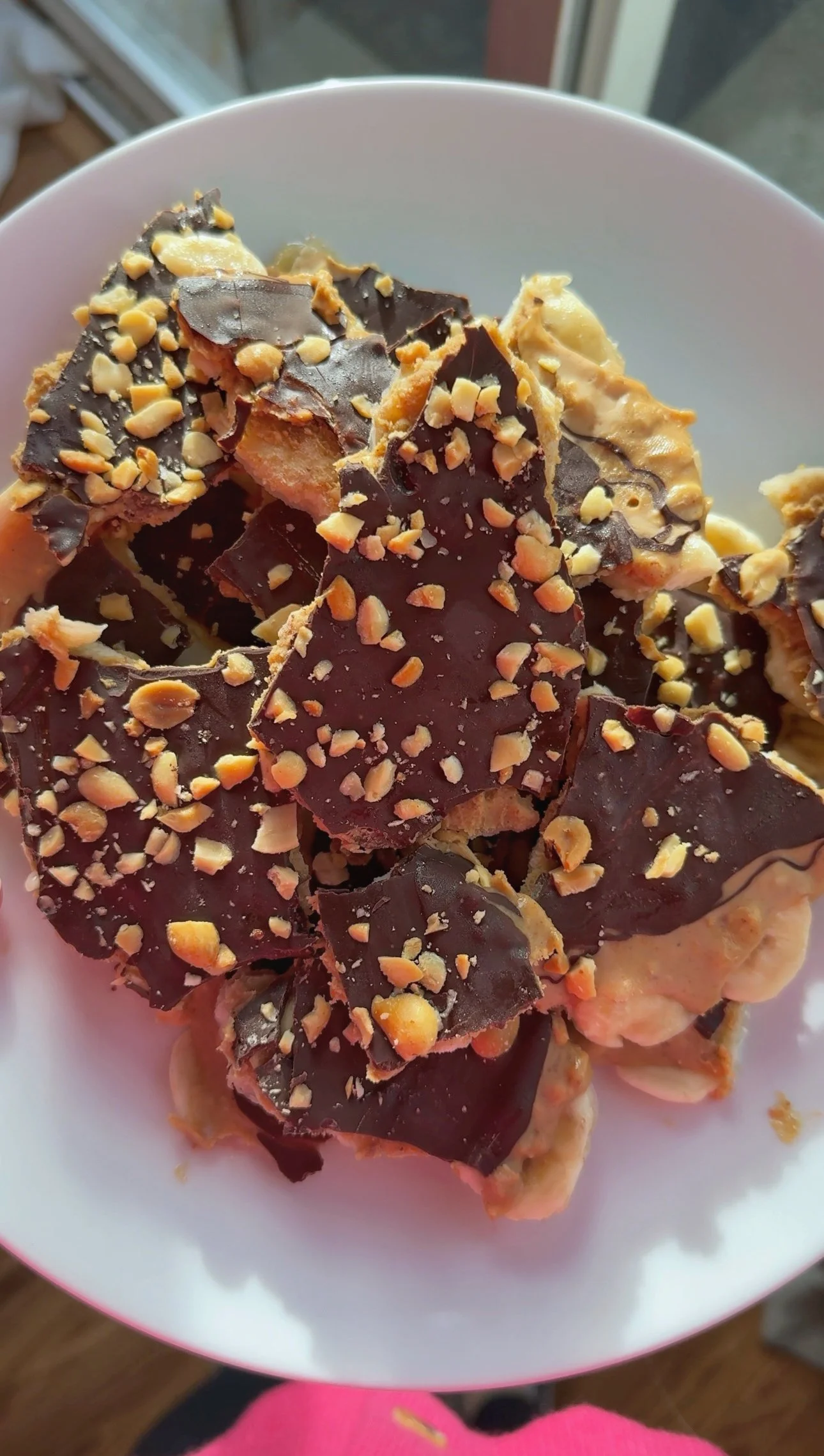A plate of chocolate covered peanut butter and banana bark topped with crushed peanuts.