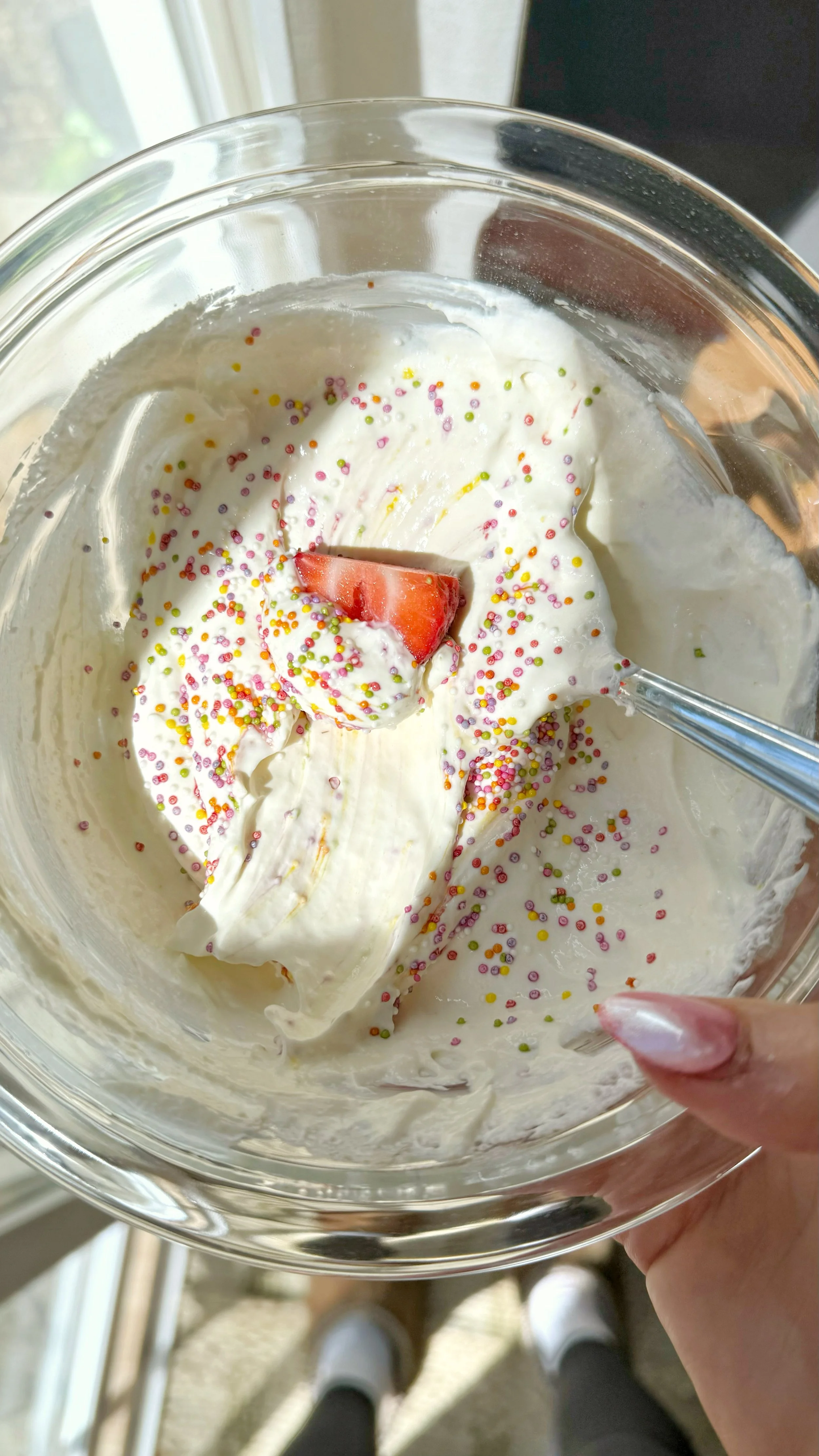 A bowl of high protein dip with a strawberry and sprinkles on top.