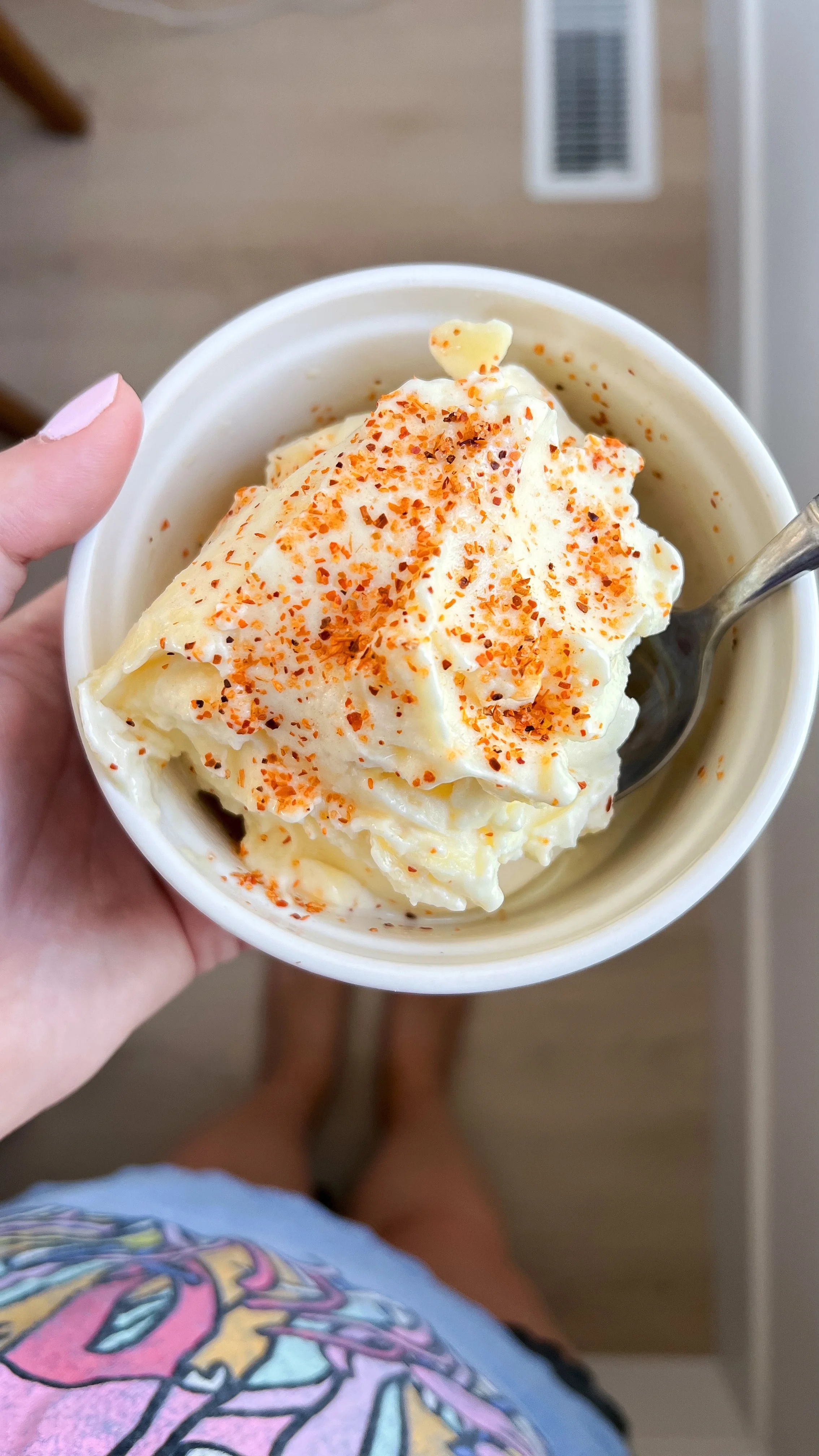 A little bowl of creamy pineapple dole whip with a sprinkle of Tajin on top.