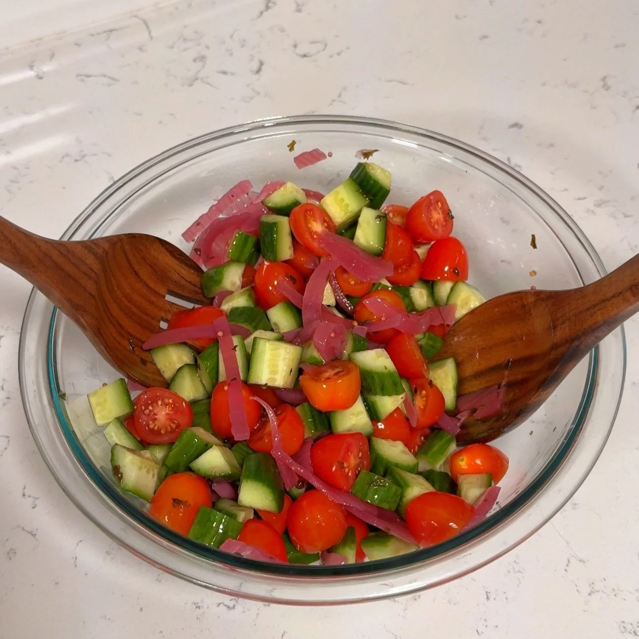 A bowl of diced tomato, cucumbers, pickled onions.