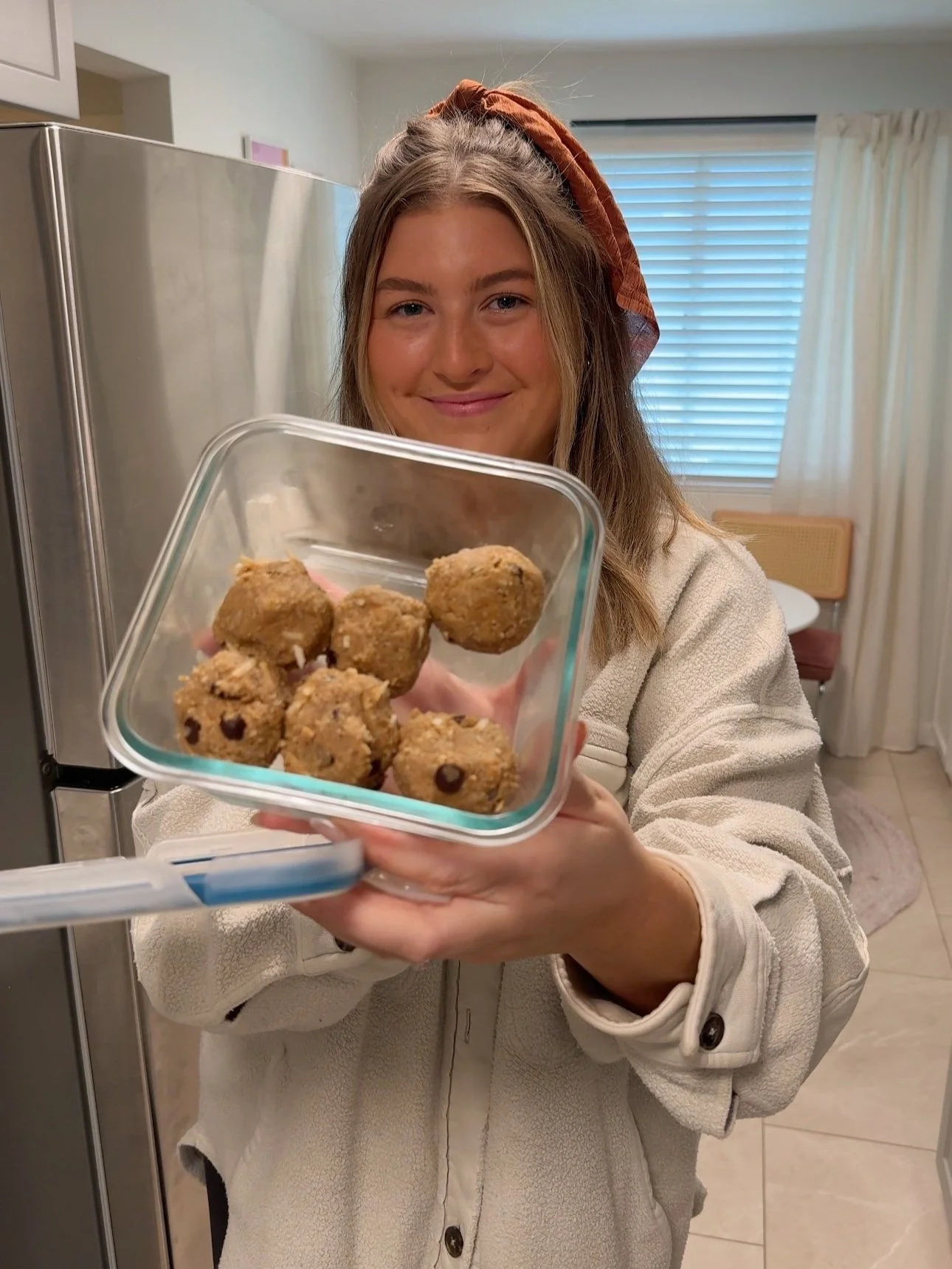 Held up to the camera is a glass dish with healthy rolled up balls that have chocolate chips in them.