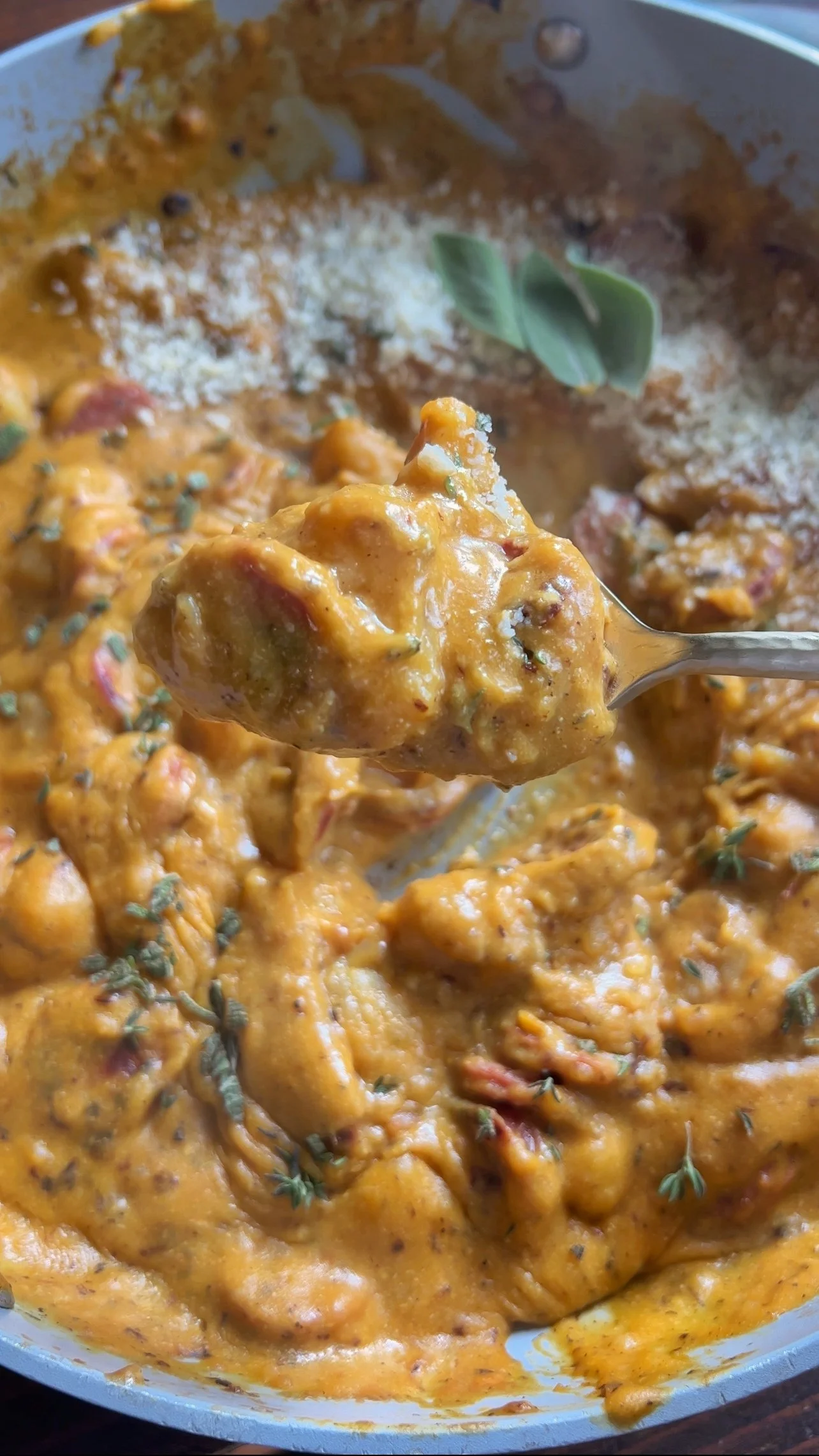 A close up shot of a pan of butternut squash with cauliflower gnocchi in it with a sprinkle of chopped sage & thyme on the top.